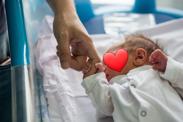 Zdjęcie przedstawia dłoń, ściskającą rączkę noworodka